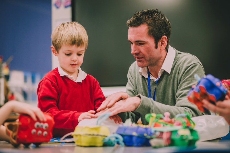 a man playing with a young child and toys in a school