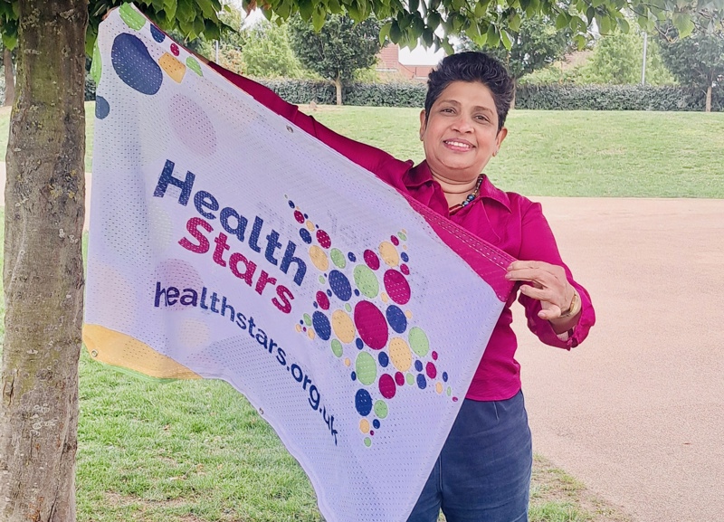 Priyanka Perera holding a flag with the Health Stars logo