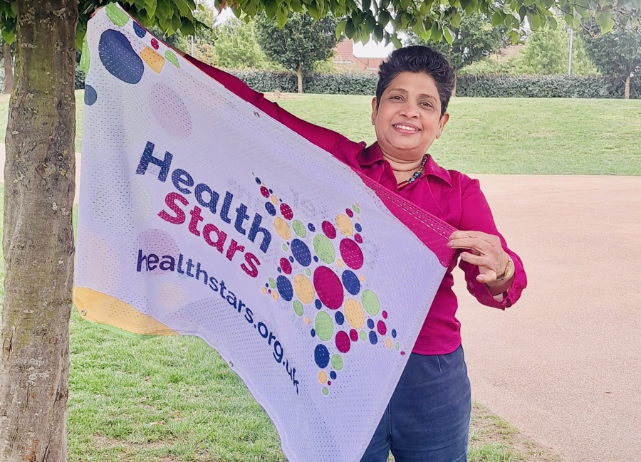 Priyanka Perera holding a flag with the Health Stars logo